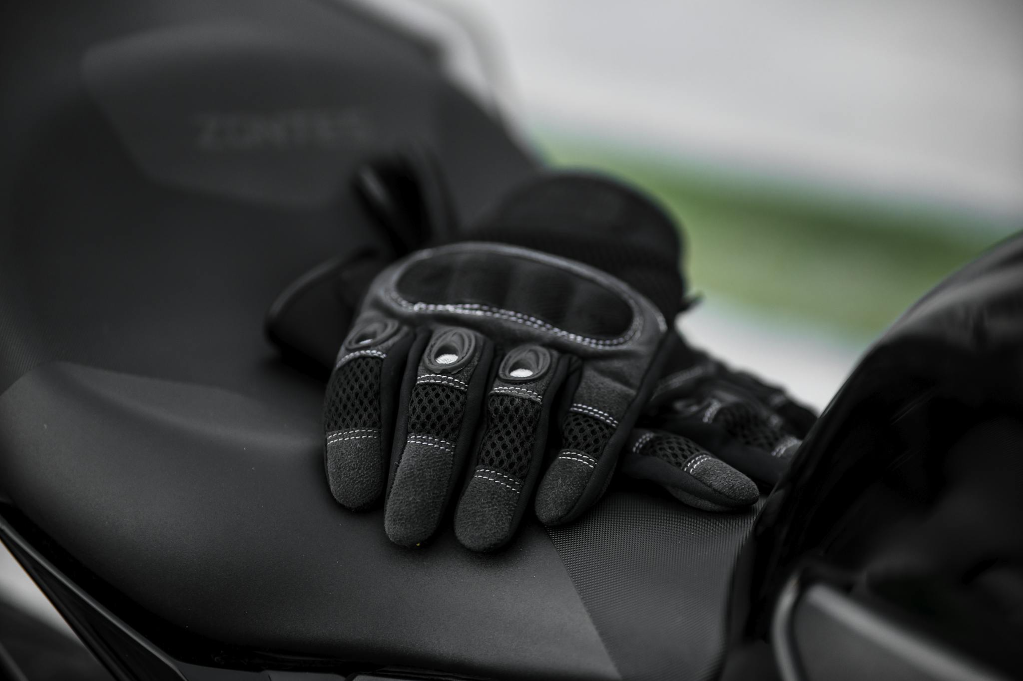 Close-up of black motorcycle gloves on a sleek motorcycle seat.